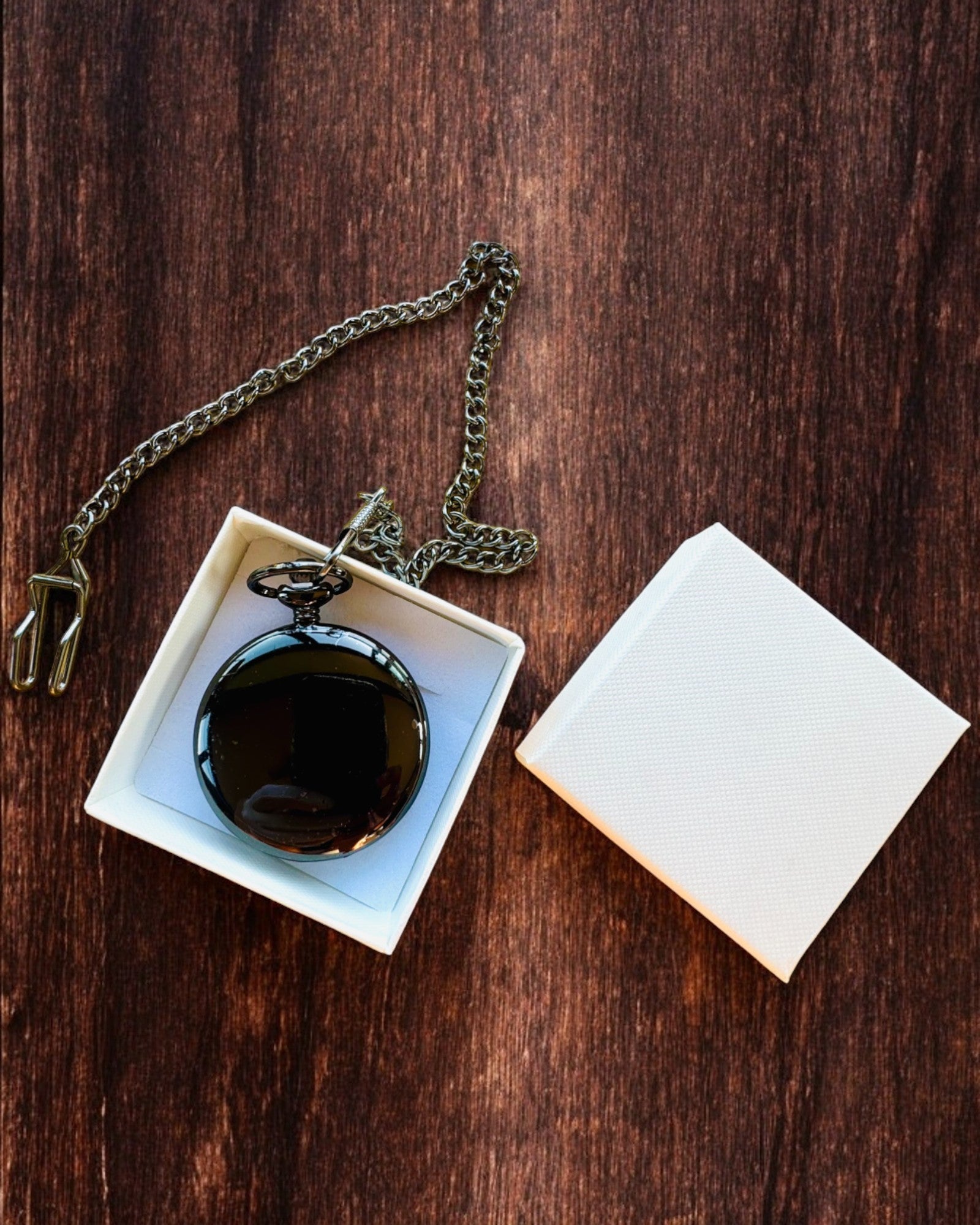 Klassinen taskukello roomalaisilla numeroilla ja ketjulla, kvartsikoneisto, musta kiilto - väri musta